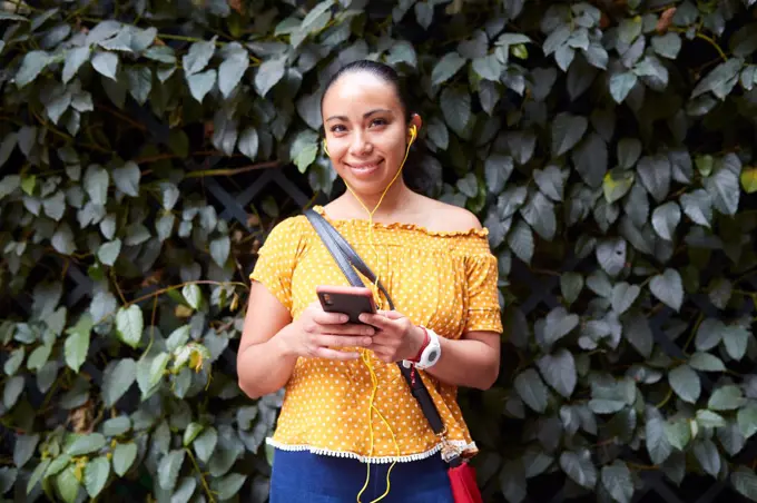 young woman listening to music through her smarthphone on the street