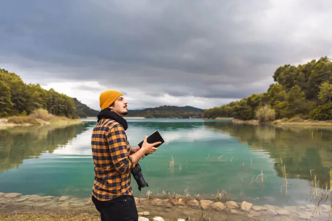 Tourist guide cheking guide book with hat and camera in the lake