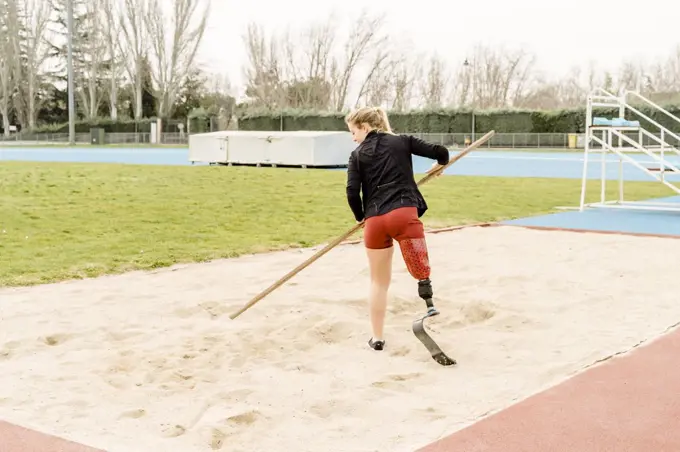Handicapped sportswoman preparing sand on stadium