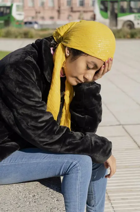 Young woman with cancer undergoing treatment. Disappointment and sadness for the bad news. Wear a yellow bandana or scarf to cover up the effects of chemotherapy.