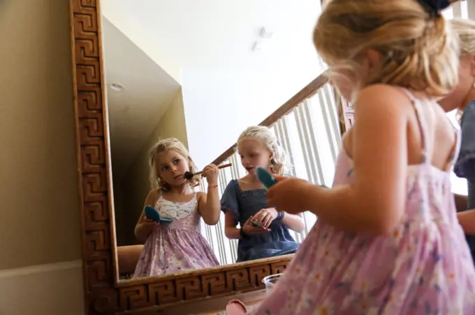 little girl look at herself in mirror putting on blush