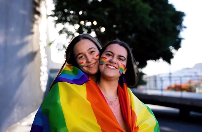 beautiful lesbian couple having fun in the street with a lgtb flag