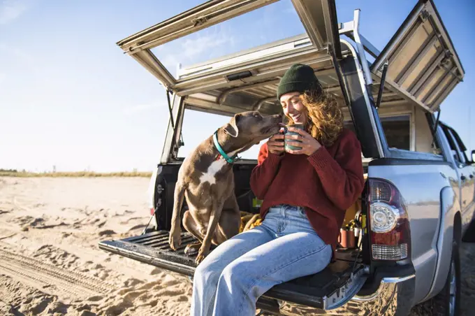 Young woman enjoying cup of coffee in the morning beach car camping