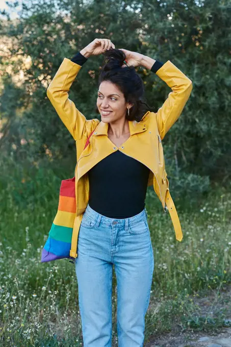 Woman posing with a handbag on her shoulder. She smiles and is outdoors.