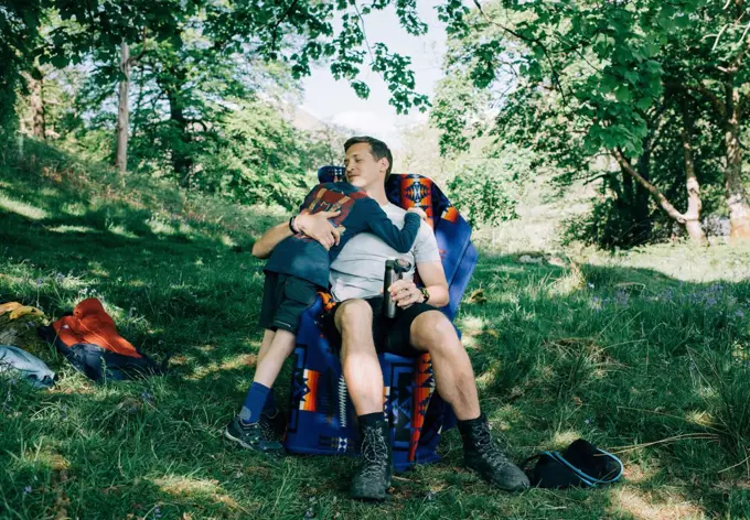 dad hugging his son whilst camping in the sunshine on vacation