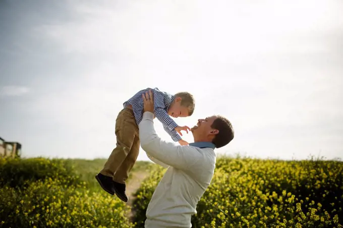 Dad Lifting Son Up in Wildflower Field