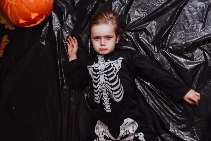 Kid boy at 5 wearing a skeleton costume at the Halloween party at home