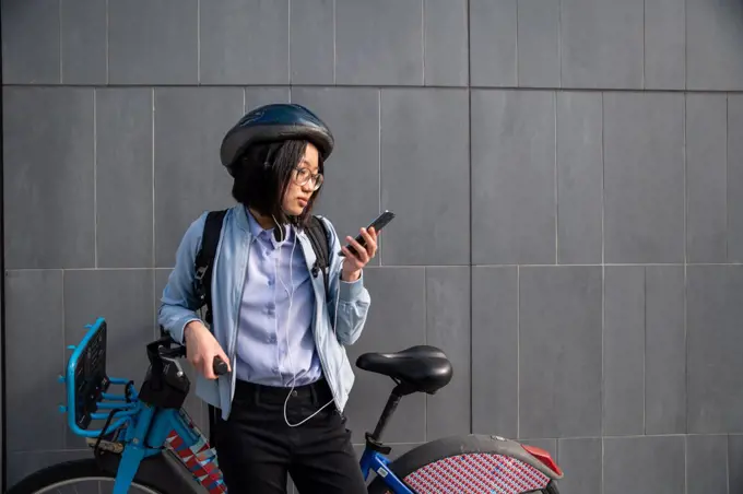 Young person looking at cell phone with urban bike rental