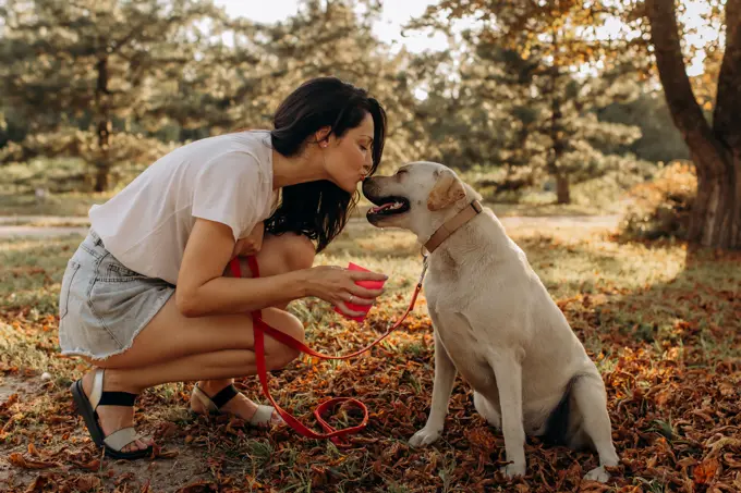 Happy woman kissing fun with her Labrador puppy outdoors