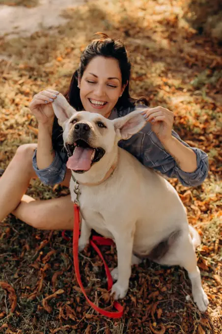 Happy woman having fun with her Labrador puppy outdoors