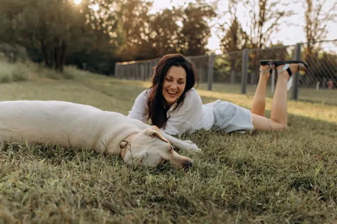 Happy woman hugging and having fun with her Labrador puppy outdoors.