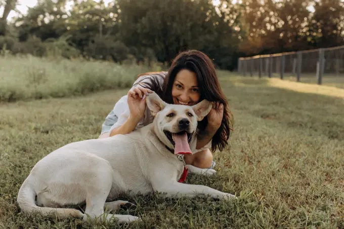 Happy woman hugging and having fun with her Labrador puppy outdoors.