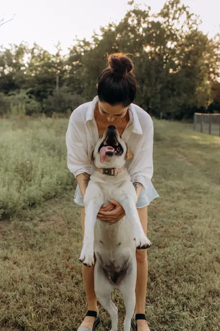 Happy young woman hugging and having fun with her Labrador  outdoors.