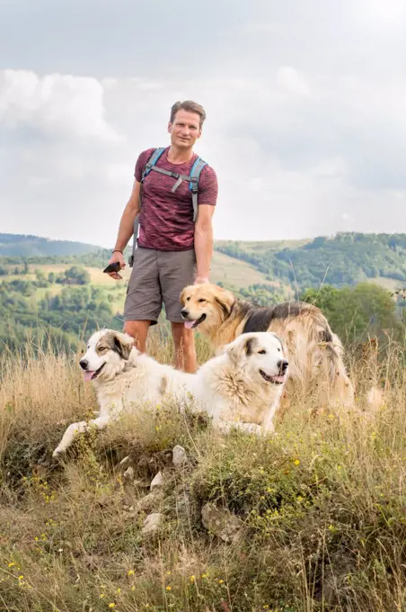 Adult man hiking in nature with shepherd dogs, on the hills in s