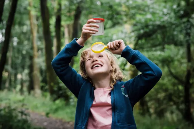 girl looking through a magnifying glass at bugs in the forest