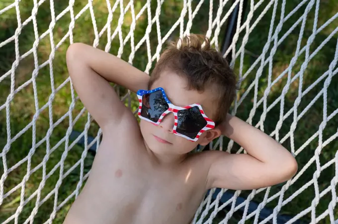 tight shot of a boy with a dreamy expression relaxing in a hammock