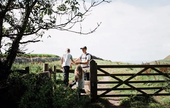 dad helping his kids climb over a stile in the english countryside