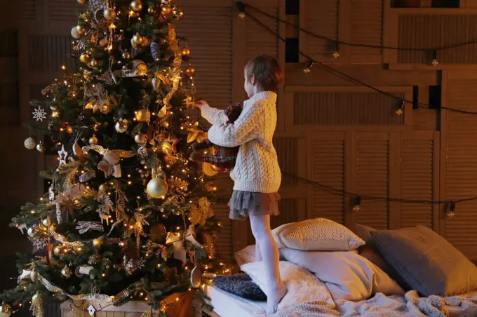 Side view of a child decorating a Christmas tree.