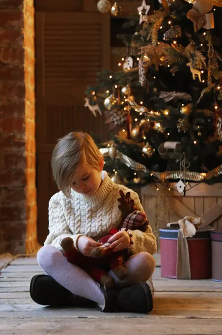 The child hugs a soft toy while sitting in warm clothes.