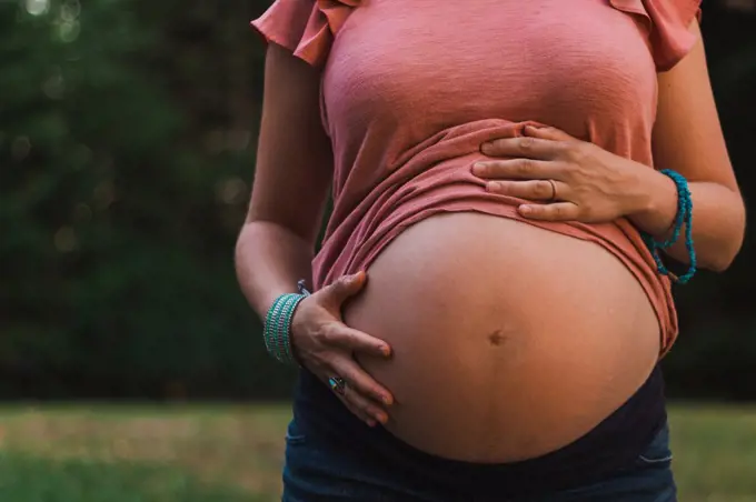 Woman Showing Pregnant Belly From Under a Top