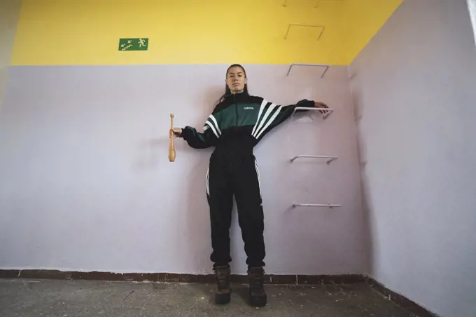 athletic androgynous strong woman holds club and looks to camera