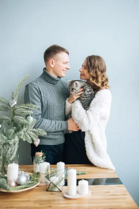 Woman and man look tender into eyes each other.Pregnant woman hold cat