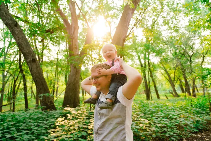 Lifestyle portrait of a baby riding on his dad's shoulders