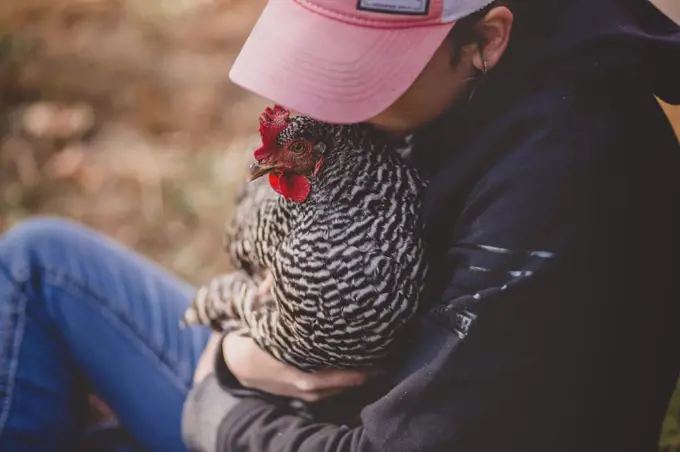 Teen girl holding chicken and kissing her