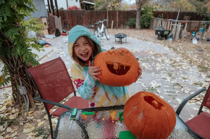 Happy young girl showing off her carved pumpkin