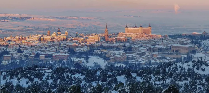 Snowy old town with castle on hill with golden colors at sunset