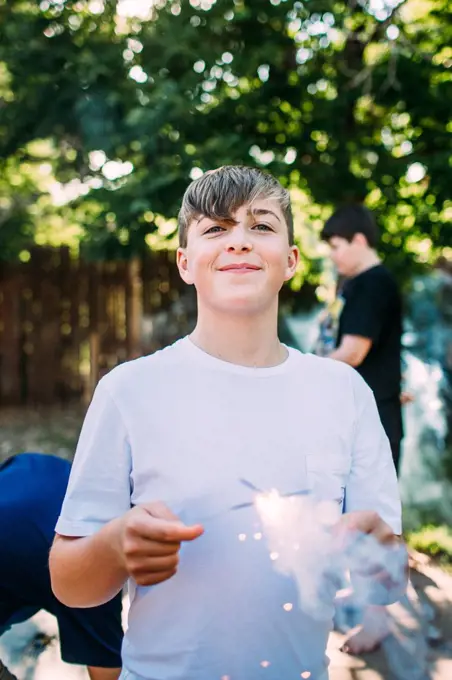 Happy teen boy playing with a sparkler outside