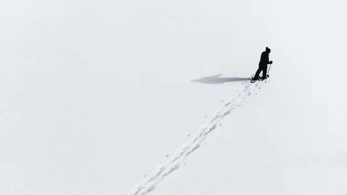 Aerial view of man snowshoeing across an empty snowy landcsape.