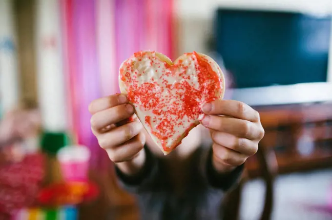 Heart sugar cookie for Valentines Day held by caucasian child hands