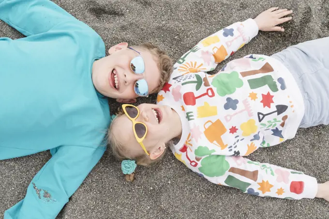 Brother and sister are lying on the beach on the sand.