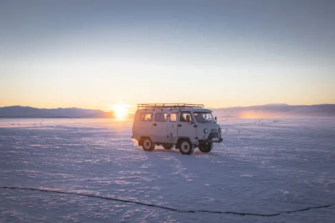 old van over frozen lake at sunset