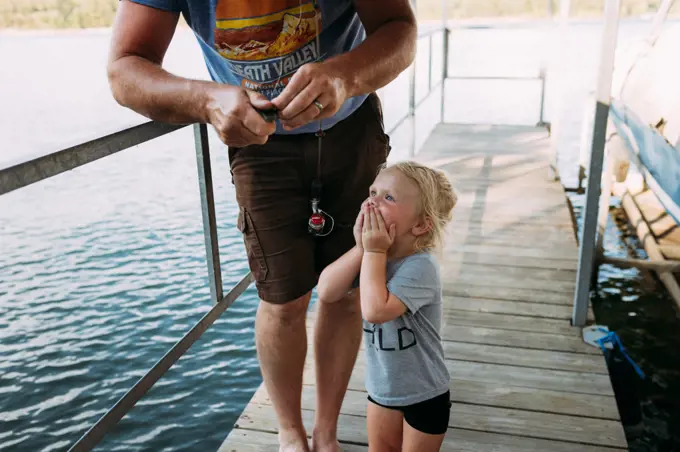 Dad getting fish off hook for excited young girl