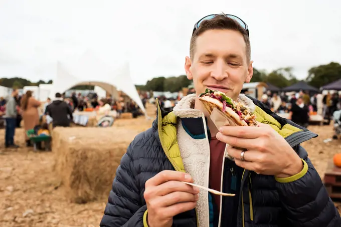 man happily eating delicious street food at a festival