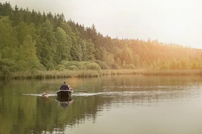 Father and son traveling in boat on lake, Bavaria, Germany