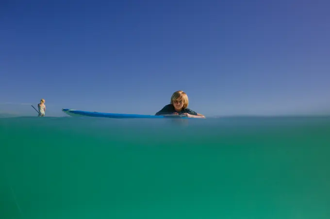 Siblings paddleboard in turquoise waters of Hawaii