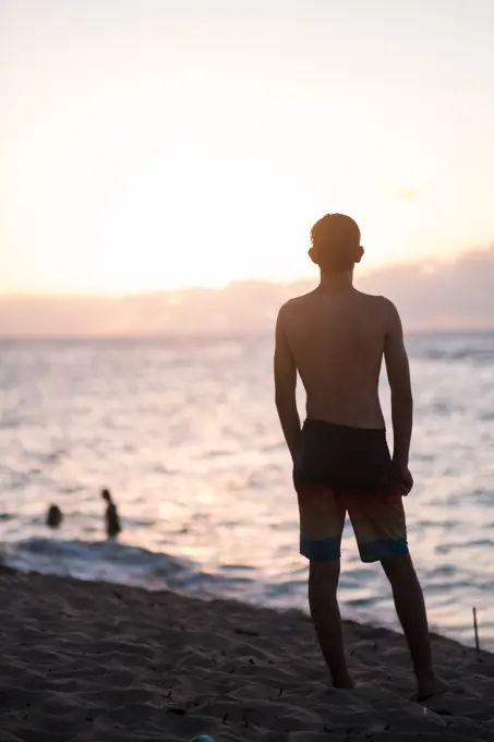 teenage boy watching the sunset on the north shore of oahu