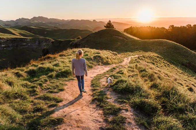 Preteen girl walking dog at sunset on Te Mata Peak in New Zealand