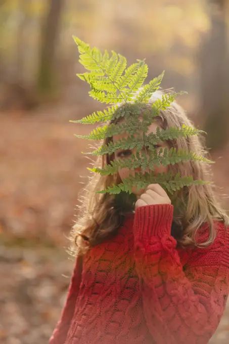 portrait of a teenage girl with a fern leaf in the autumn forest