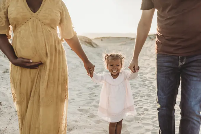 Young family of three walking and playing at beach