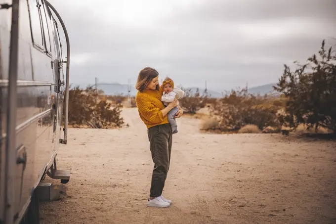 A woman with a baby is near an RV trailer, Joshua Tree, California