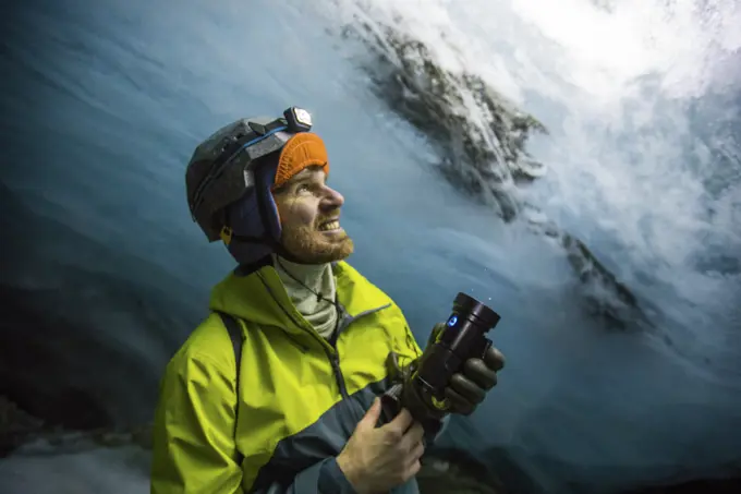 Explorer shines light on glacier above, illuminating the blue colours