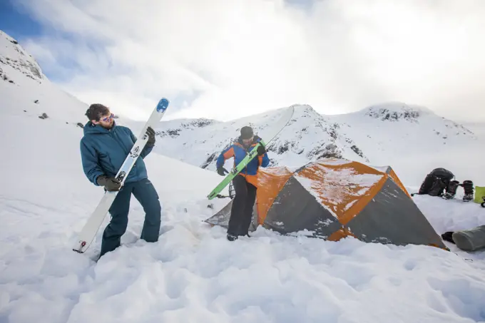 Two skiers use their skis as air guitars, jam session at basecamp