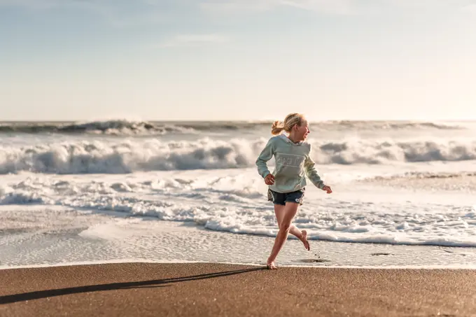 Girl laughing and running on beach in New Zealand