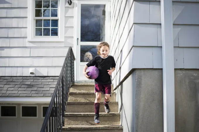 Girl running down stairs with soccer ball