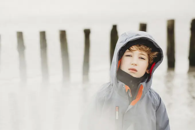 Portrait of cold boy on beach in winter