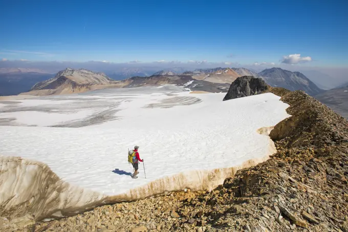 high angle of backpacker hiking across tip of huge glacier.